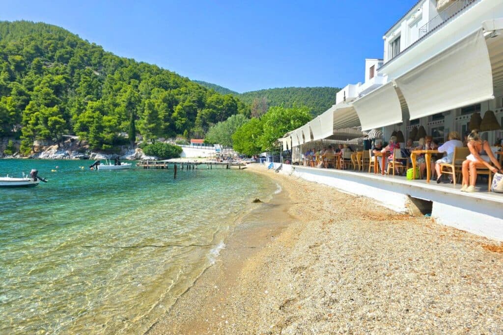 Tavernas along the sea with pine covered mountains in the distance