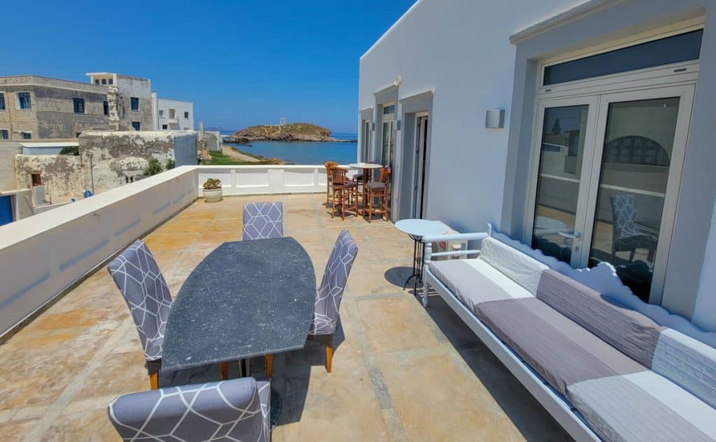 A large terrace with dining table overlooking the ocean and portara in Naxos island greece