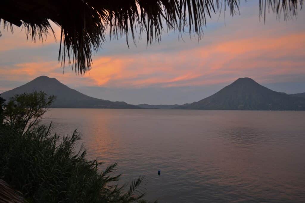 Sunrise view with pink sky of Lake Atitlan Guatemala and twin volcanoes
