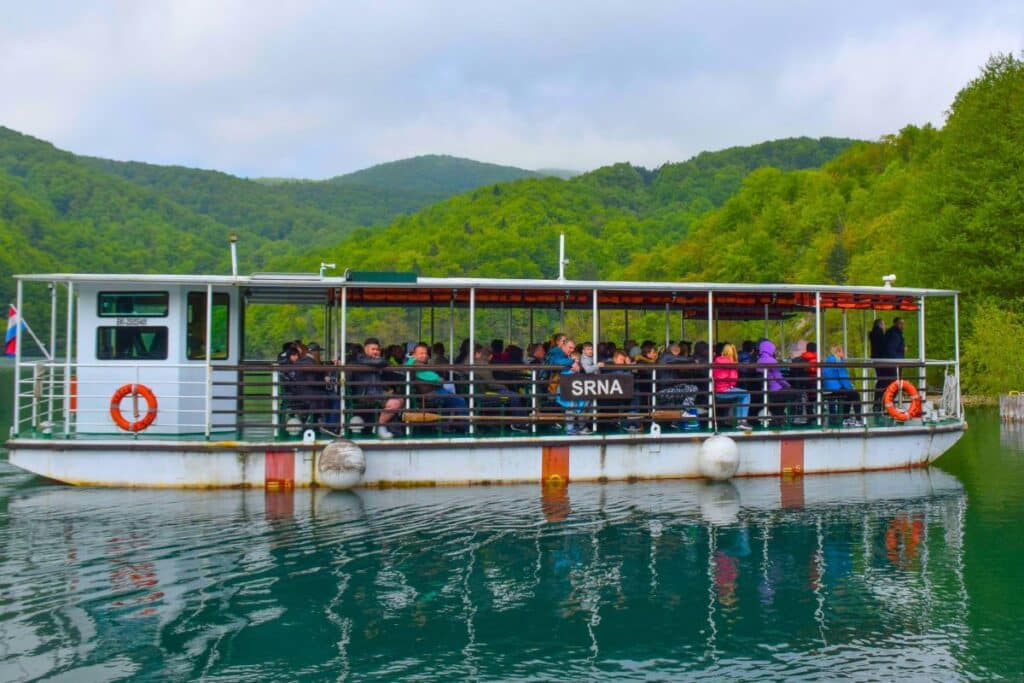 A riverboat full of people crosses the lake at Plitvice Lakes National Park in Croatia