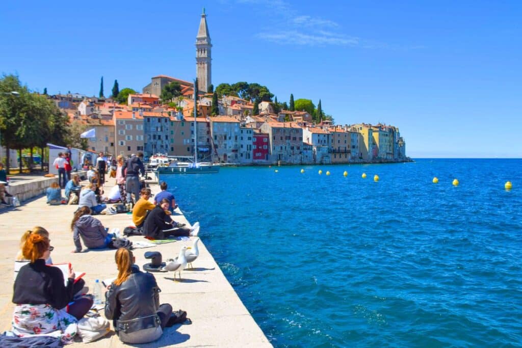 Art students sitting by the sea sketching the colors of Rovinj