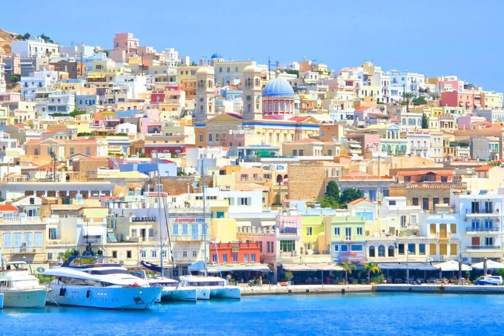 Pastel colored neoclassical buildings lining the side of a mountain in Syros Island Greece